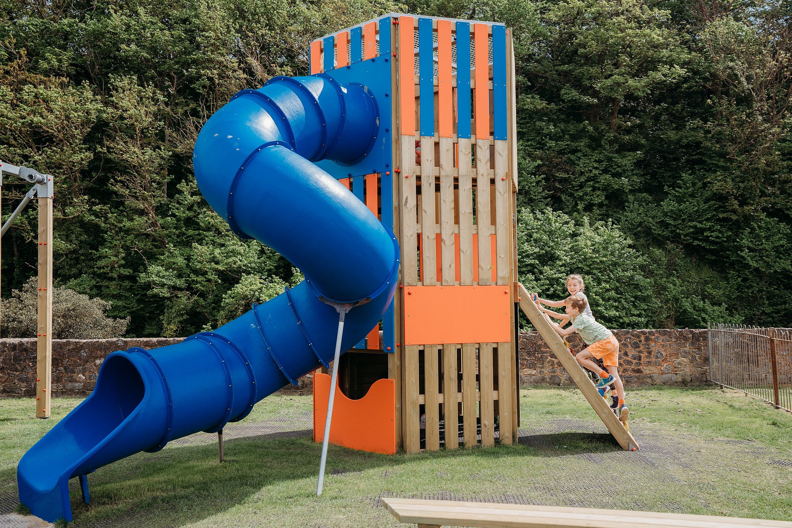 3m high Spiral Slide & tower with children climbing up the climbing wall.